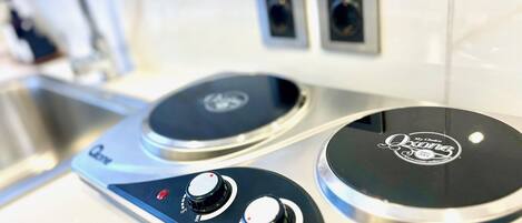 A kitchen with two induction cooktops, a sink, and a faucet.