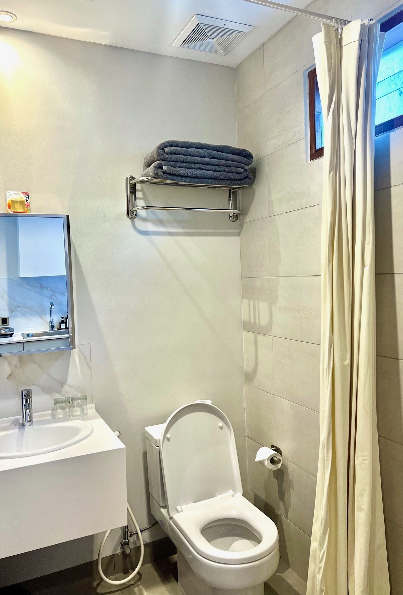 A modern bathroom with a white sink, toilet, and shower curtain.