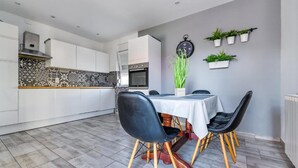A modern kitchen with white cabinets, a patterned backsplash, and a dining area with a table and chairs. - Lovely home in Privlaka (Privlaka)