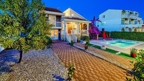 A two-story house with a swimming pool, a covered patio, and a well-maintained garden. - Lovely home in Privlaka (Privlaka)