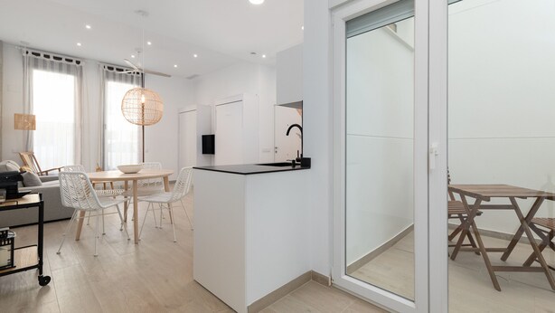 A modern, minimalist living space with a kitchen area, dining table, and seating. - Ca Celieta Beach I WiFi+ Air Condition (Valencia)