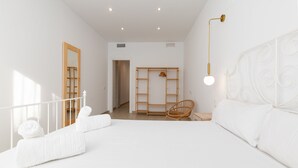 A spacious bedroom with a large bed, a wooden wardrobe, a wicker chair, and a bedside table. - Ca Celieta Beach II. WiFi+ Aire Acondicionado (Valencia / València)