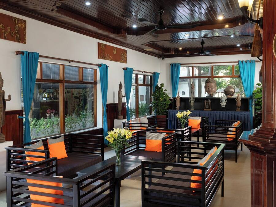 A traditional room with wooden furniture, a Buddha statue, and a large window with curtains.