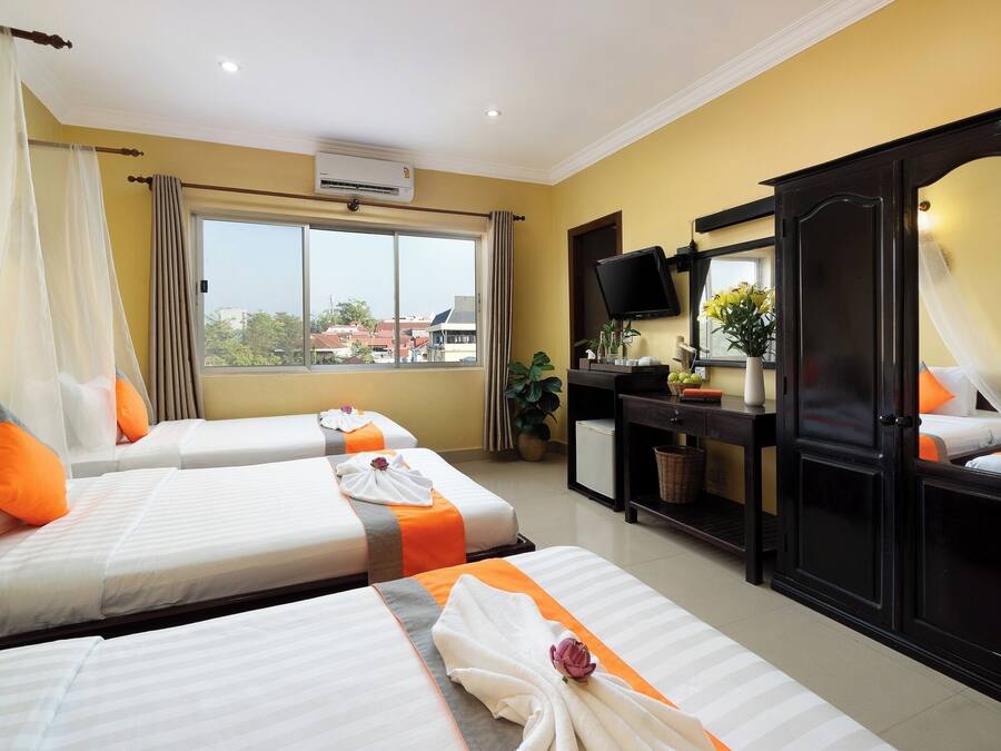 A hotel room with two beds, a desk, a TV, and a large mirror.
