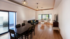 A spacious living room with a dining area, large windows, and a flat-screen TV. - FLH Caparica Town House with Pool (Charneca de Caparica)
