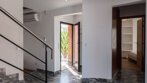 A modern interior with a marble staircase, a door leading to a room with a bed, and a visible outdoor area with a plant. - FLH Caparica Town House with Pool (Charneca de Caparica)