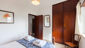 Une chambre à coucher avec un lit, une chaise, une armoire et un miroir.