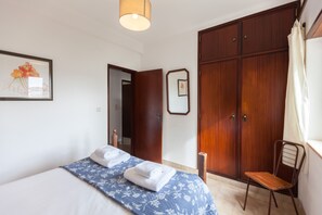 Une chambre d’hôtel avec un lit, une chaise, une armoire et un miroir.