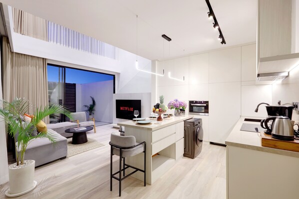 A modern, open-plan living and dining area with a sofa, coffee table, and a small kitchen island.