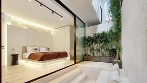 Ein modernes Schlafzimmer mit Bett, einer Couch und einer Treppe, die zu einem Balkon mit Pflanzen führt.