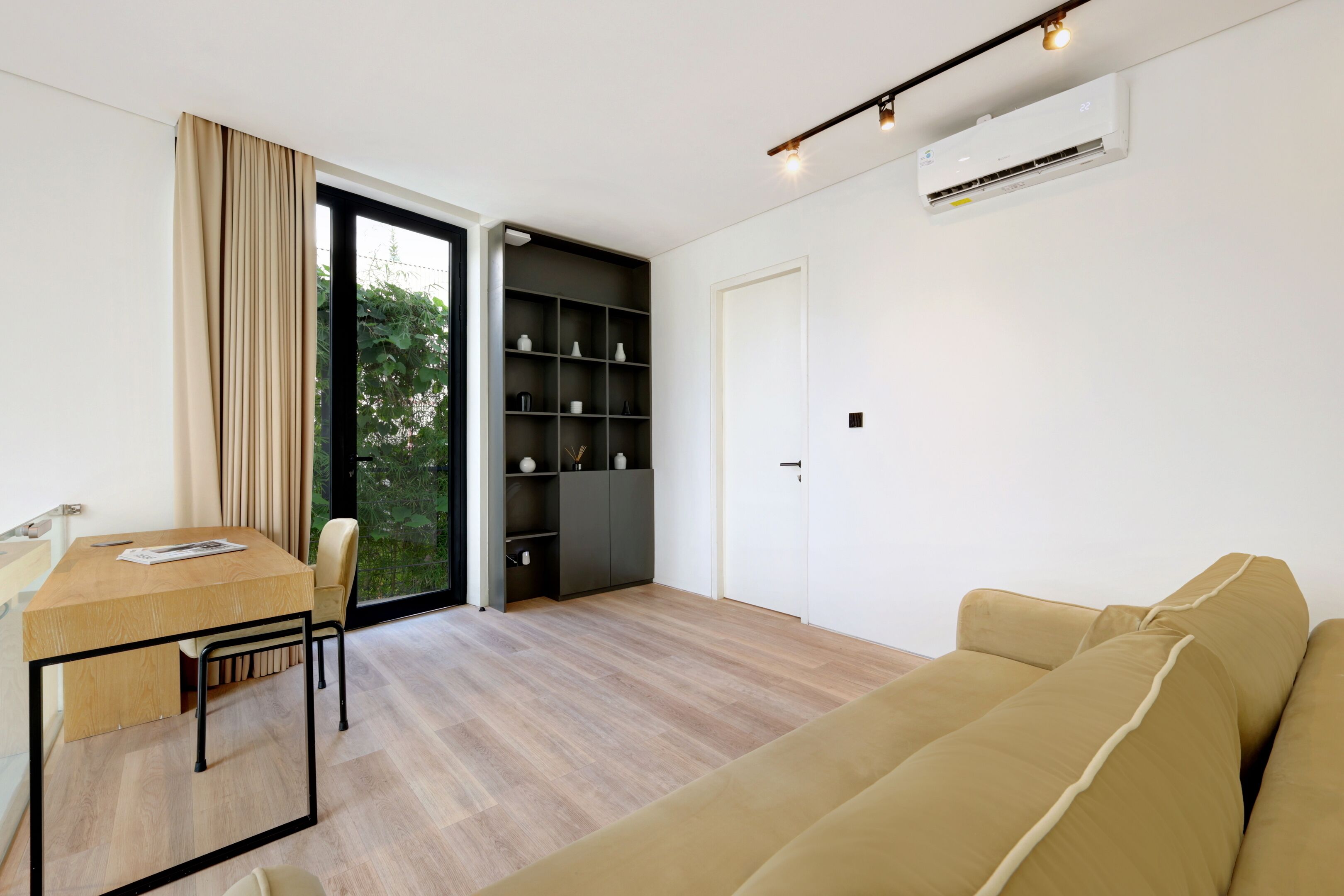 Una sala moderna con una mesa de comedor de madera, un sofá beige y una estantería empotrada.