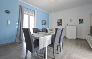 Ein Essbereich mit einem Tisch für vier Personen, Stühlen, einer weißen Kommode und Kunstwerken an den Wänden.
