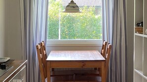 A dining table with six chairs, a hanging pendant light, and a window with curtains. - Beautiful home in Färjestaden with WiFi (Färjestaden)