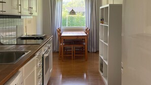 A kitchen with a wooden table and chairs, white cabinets, and a window with curtains. - Beautiful home in Färjestaden with WiFi (Färjestaden)