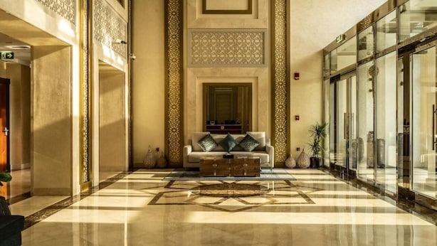 Eine Lobby mit Schachbrettmuster-Boden, einer Couch mit Kissen und dekorativen Vasen.