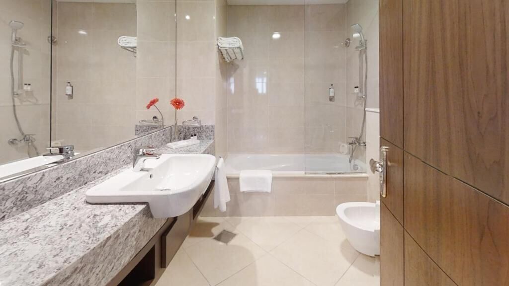 Et moderne badeværelse med bordplade i marmor, badekar og toilet.