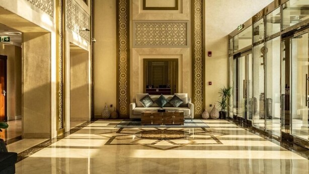 A lobby with a checkered floor, a sofa with cushions, and decorative wall panels.