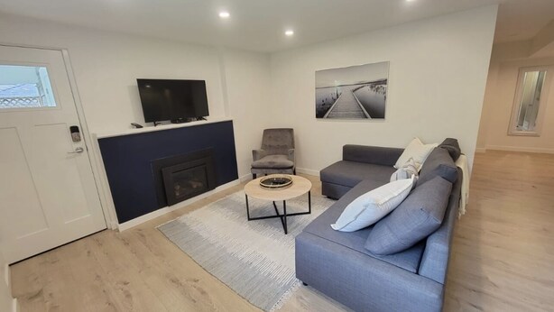 Ein modernes Wohnzimmer mit grauem Sofa, Couchtisch, grauem Sessel und flachbildfernseher an der Wand.