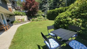 Ein gepflegter Garten mit Rasenfläche, einem Tisch mit Stühlen und einem kleinen Gartenbereich.