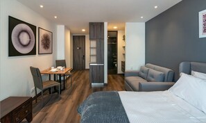 Relax in this stylish room with a large bed, sofa, and dining area, featuring a wardrobe and framed artworks.