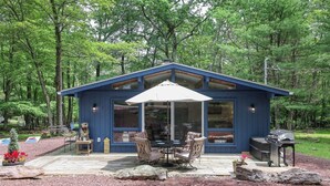 A blue cabin with a patio, a dining table, chairs, and a grill. - KingBed+Cabin+quiet+new renovation+foliage+ski (Lake Harmony)