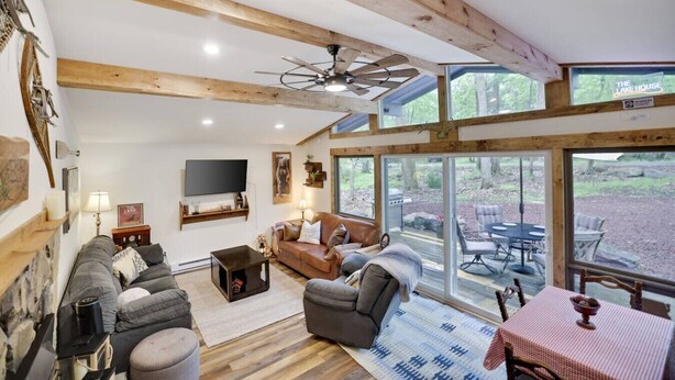 A spacious living room with a fireplace, comfortable seating, and large windows offering a view of the outdoors. - KingBed+Cabin+quiet+new renovation+foliage+ski (Lake Harmony)