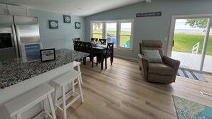 Una cocina moderna con encimeras de granito, un comedor con mesa y sillas, un sofá de cuero y vistas al exterior.