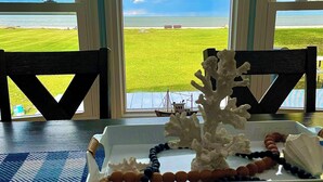 Una mesa con una bandeja que contiene un coral decorativo, un collar de cuentas y una concha marina.