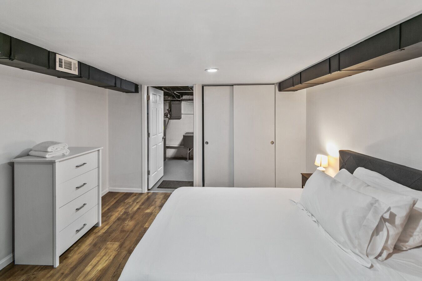A bedroom with a bed, a dresser, a nightstand, and a closet.