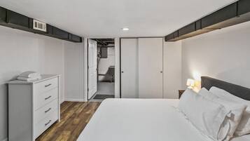 A bedroom with a bed, a dresser, a nightstand, and a closet.
