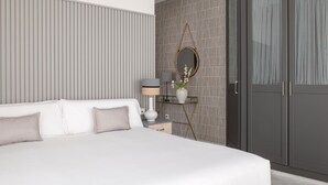 Un dormitorio moderno con una cama grande, una mesita de noche con lámpara, un espejo y un armario.