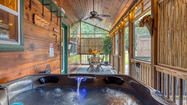 Ein Whirlpoolbereich mit Holzwänden, einem Deckenventilator und Blick ins Freie.
