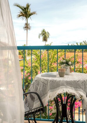 A balcony with a table covered by a lace tablecloth, a potted plant, and a storage bag. - Hoi An Lazy Bear Hostel (Da Nang)