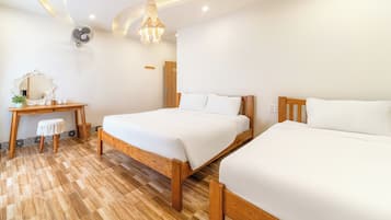 Ein Hotelzimmer mit zwei Betten, einem Holztisch, einem Stuhl, einem Spiegel und einem Deckenventilator.
