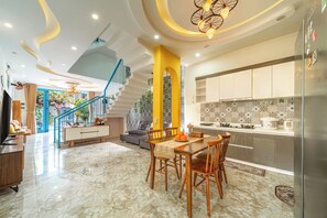 A modern kitchen with a dining area, a staircase, and a living room with a TV. - Hoi An Lazy Bear Hostel (Da Nang)