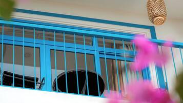 Una habitación con barandilla azul, lámpara colgante y ventana con cortinas.