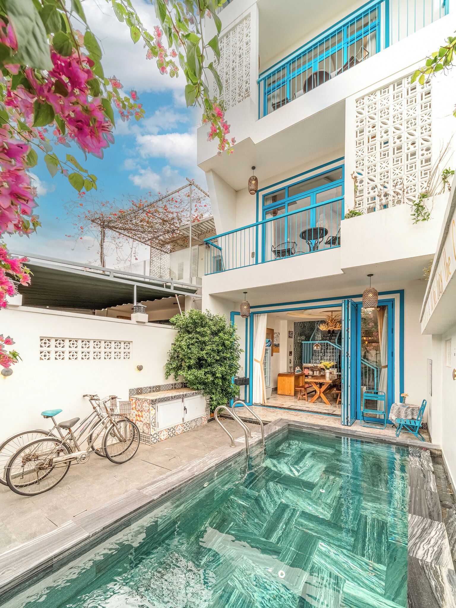 A two-story building with a swimming pool, a bicycle, and a balcony with blue railings.