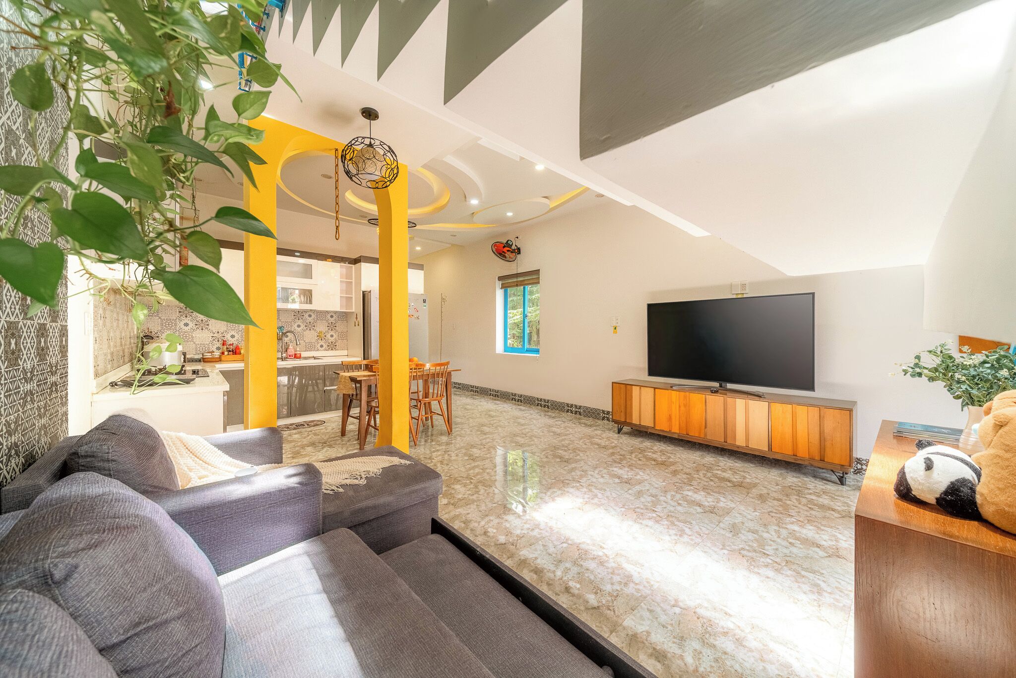 Una sala de estar con sofá, televisor y comedor con sillas.