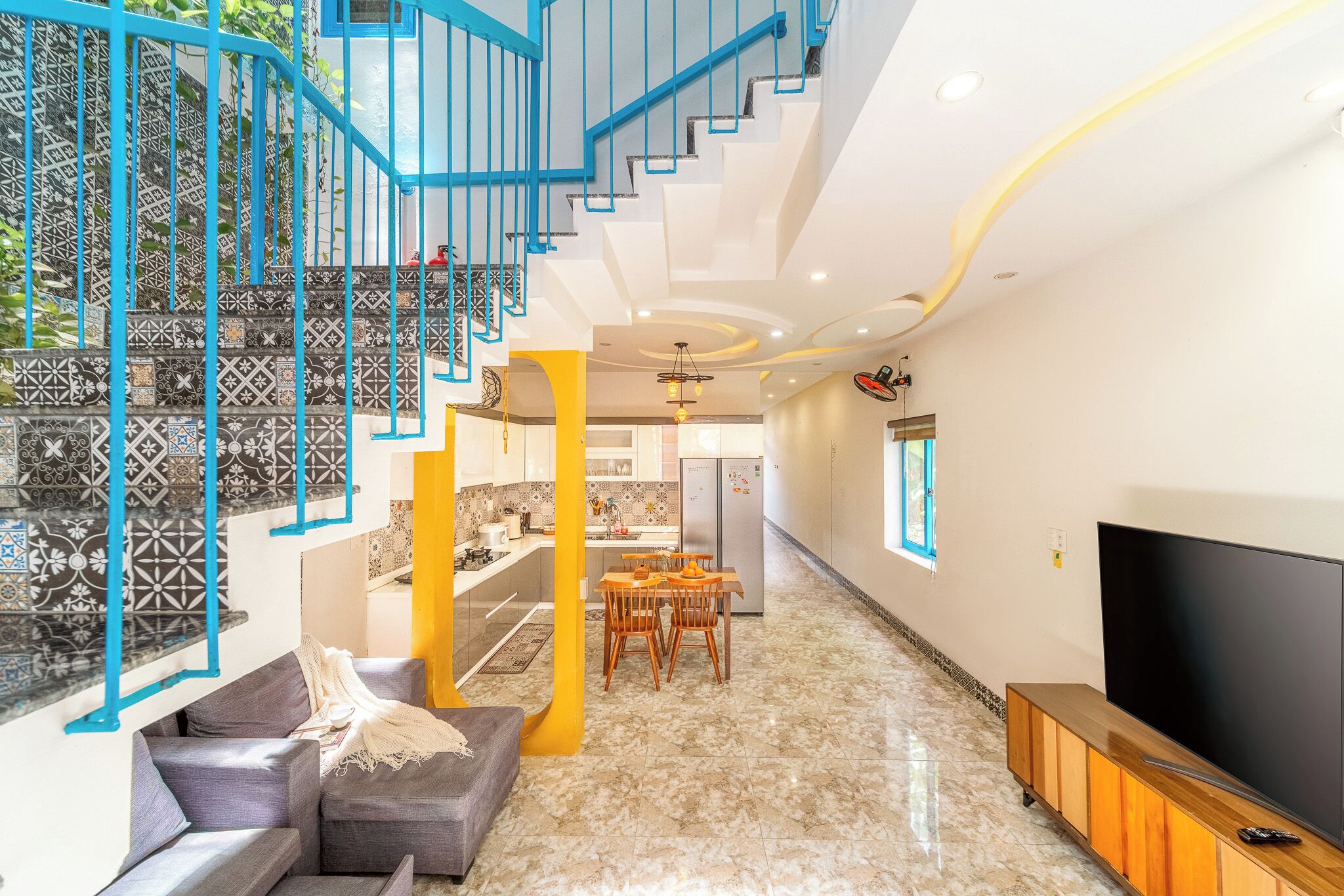 A modern living room with a staircase, a dining area, and a TV.
