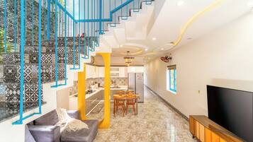 A modern living room with a staircase, a dining area, and a TV.