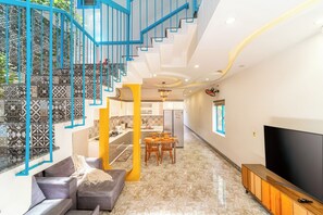 Un salon moderne avec un escalier, un coin repas et un téléviseur.