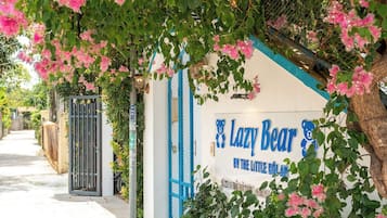 A pathway leading to a building with a sign reading 'Lazy Bear' and a blue gate.
