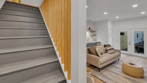A modern interior with a grey staircase, wooden paneling, a beige sofa, and a round coffee table. - Charming Guest House - Dog Friendly - Parking (Wilmington)