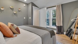 A bedroom with a bed, pillows, a window with curtains, a hanging chair, and wall-mounted planters. - Charming Guest House - Dog Friendly - Parking (Wilmington)