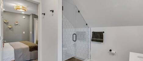 A modern bathroom with a glass shower enclosure, a toilet, and a sink.