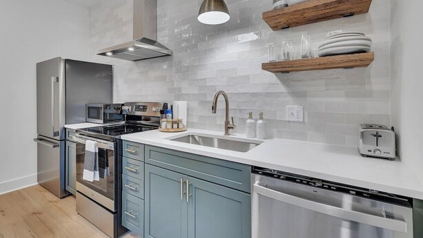A modern kitchen with stainless steel appliances, a double sink, and wooden shelves. - Charming Guest House - Dog Friendly - Parking (Wilmington)