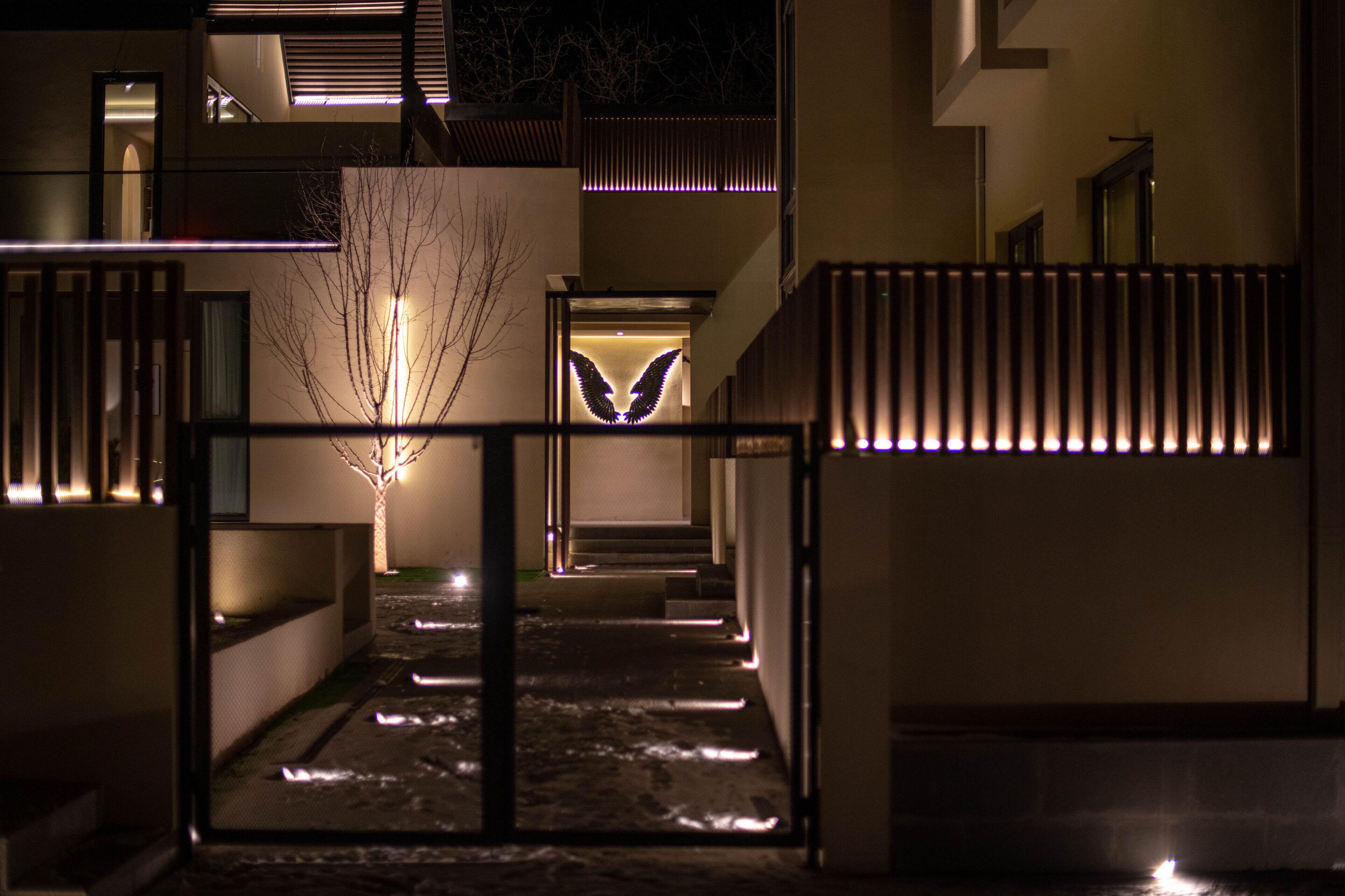 A modern building with a gated entrance, a staircase, and illuminated architectural features.