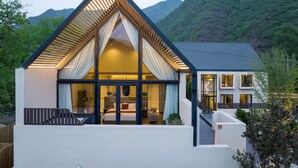 Una casa moderna con un amplio ventanal, un techo triangular llamativo y vistas a un paisaje montañoso.