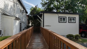 A wooden walkway leading to a small laundry facility with a sign.