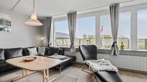 A modern living room with a sofa, a dining table, and a recliner.